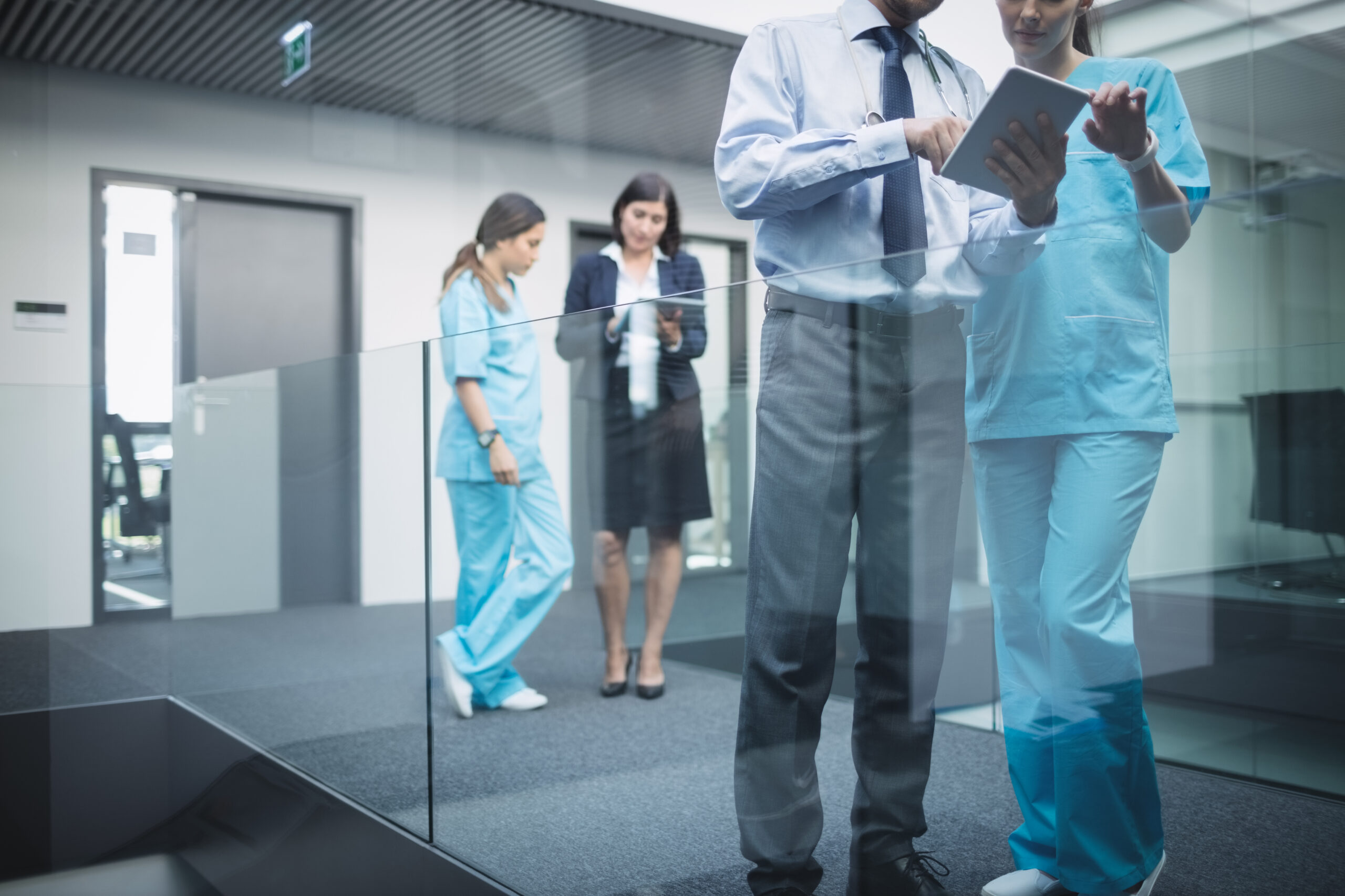 Doctors and nurses discussing over digital tablet in hospital corridor